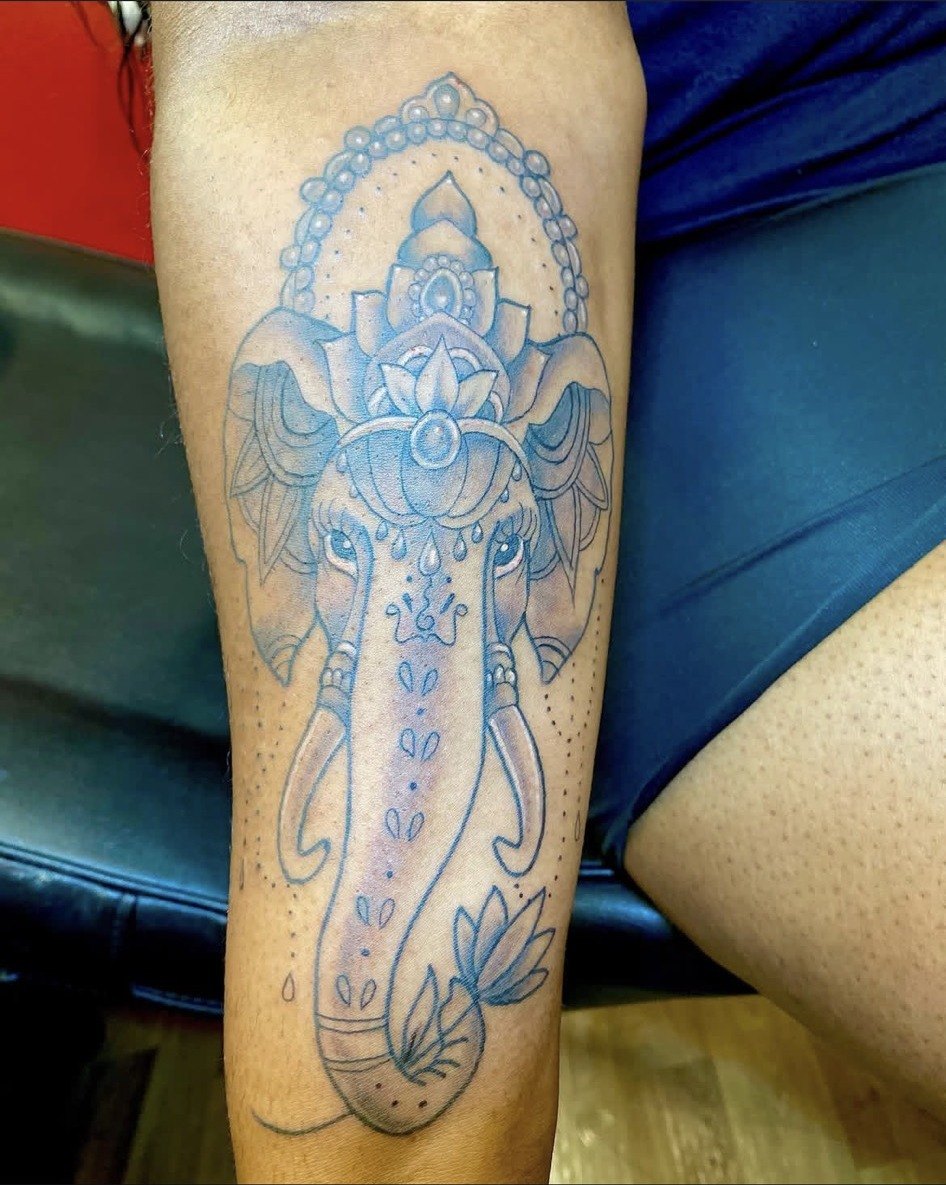 Black and grey ornamental elephant tattoo with lotus details on a forearm