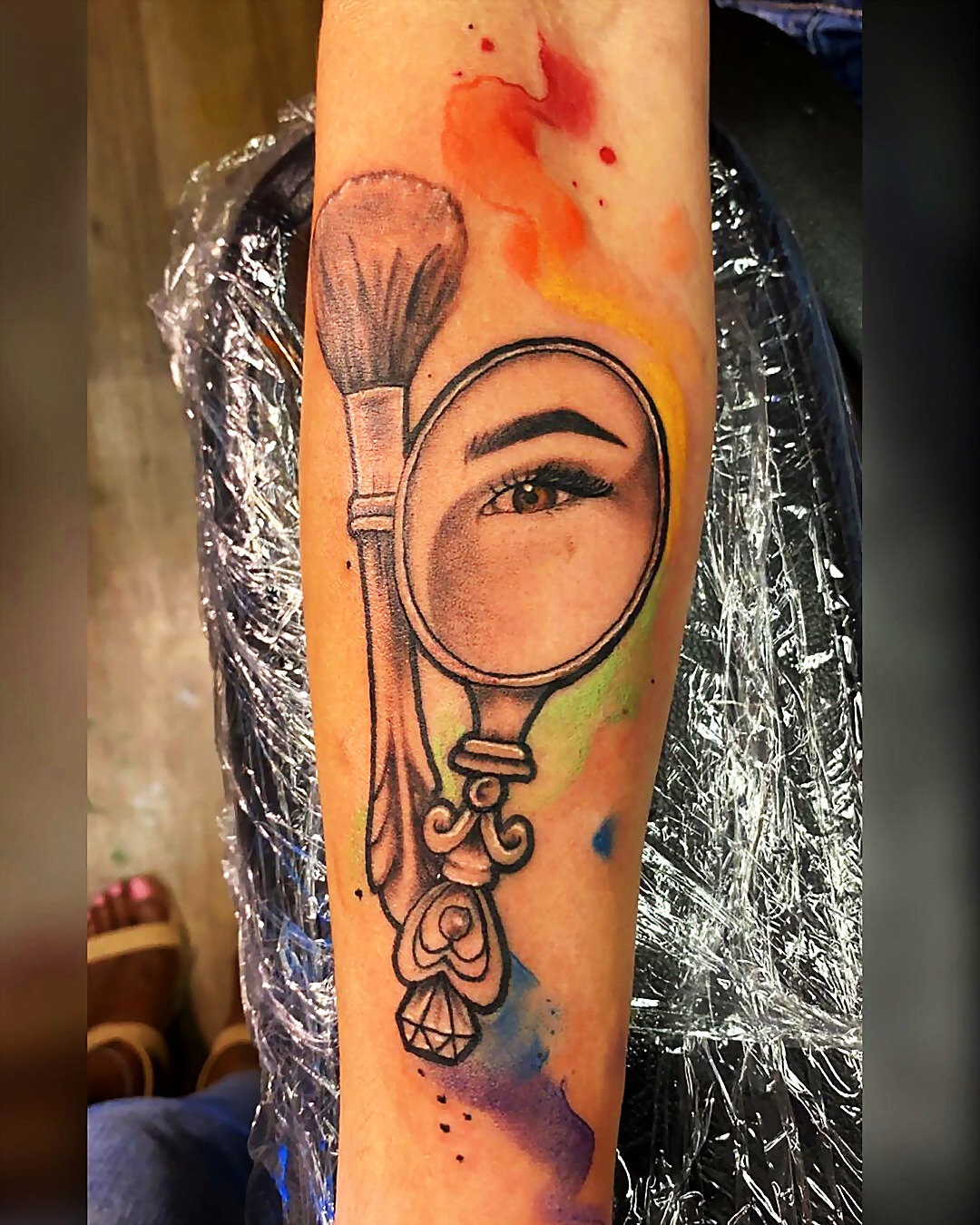 Watercolor realism tattoo of a hand mirror and brush