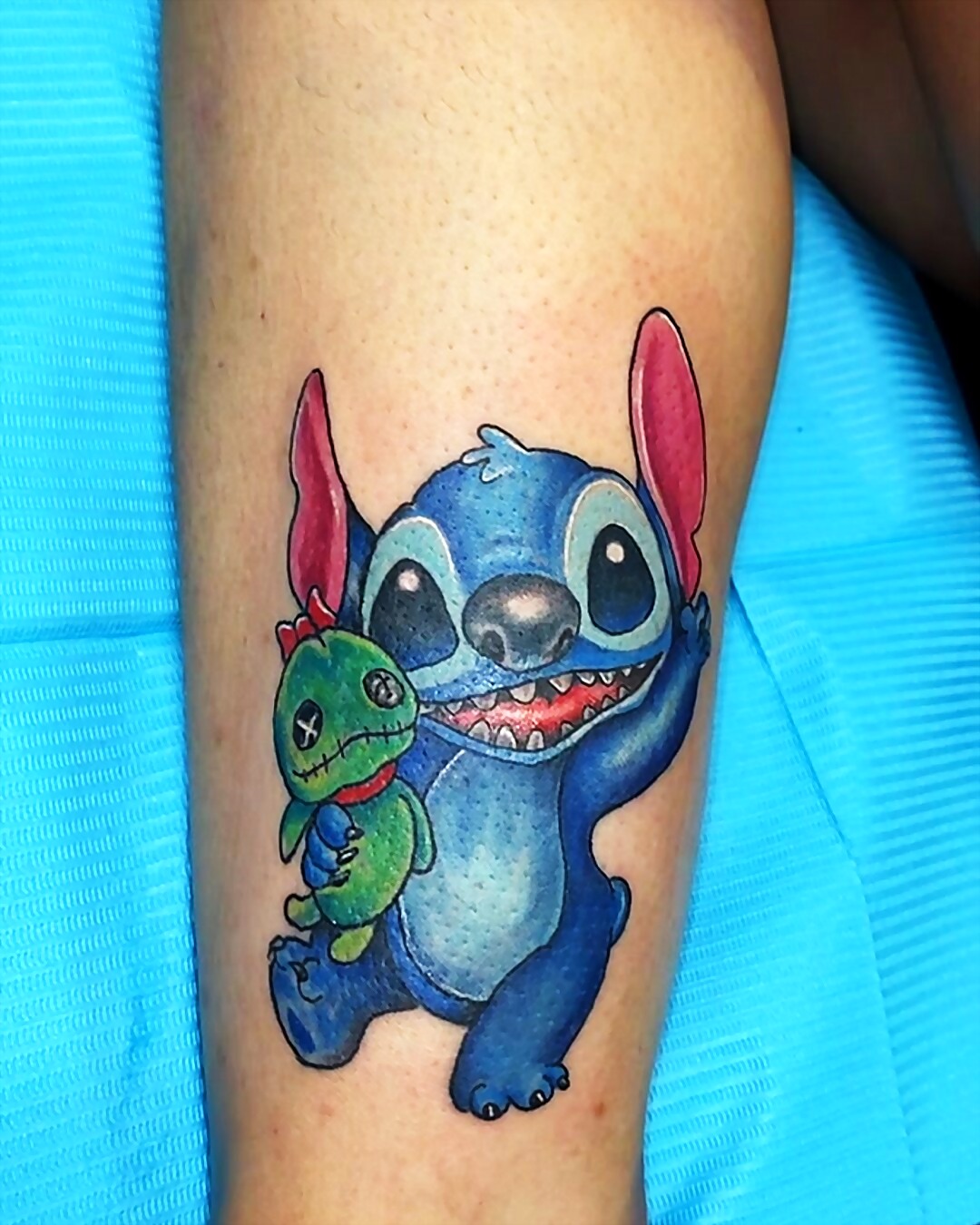 Full color calf tattoo of Stitch holding Scrump